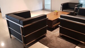 A modern room with a wooden coffee table, black leather sofas, and a small potted plant. - Apatel The OAK Tower Pulo Gadung (Jakarta)