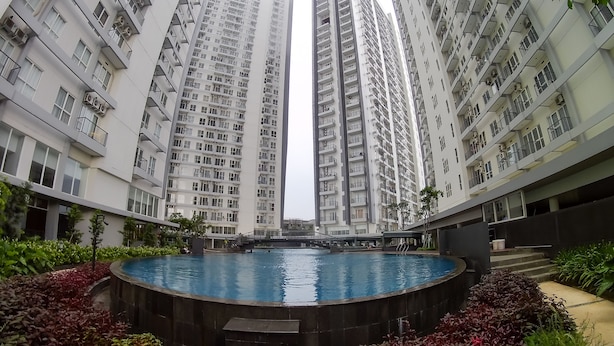 Un immeuble résidentiel de grande hauteur doté d’une piscine centrale, le tout entouré d’une végétation luxuriante.