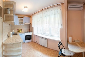A compact kitchen with a gas stove, a built-in oven, and a window with sheer curtains. - Apart Kiev Klovskiy spusk 12 (Kyiv)