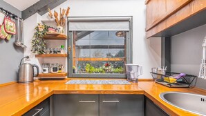 Una cocina con encimera de madera, electrodomésticos de acero inoxidable y un ventanal con vistas a la vegetación.