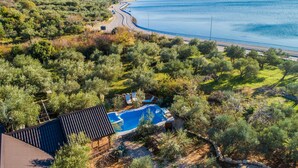 Una propiedad costera con piscina, rodeada de vegetación exuberante y vistas al mar y al puerto deportivo.