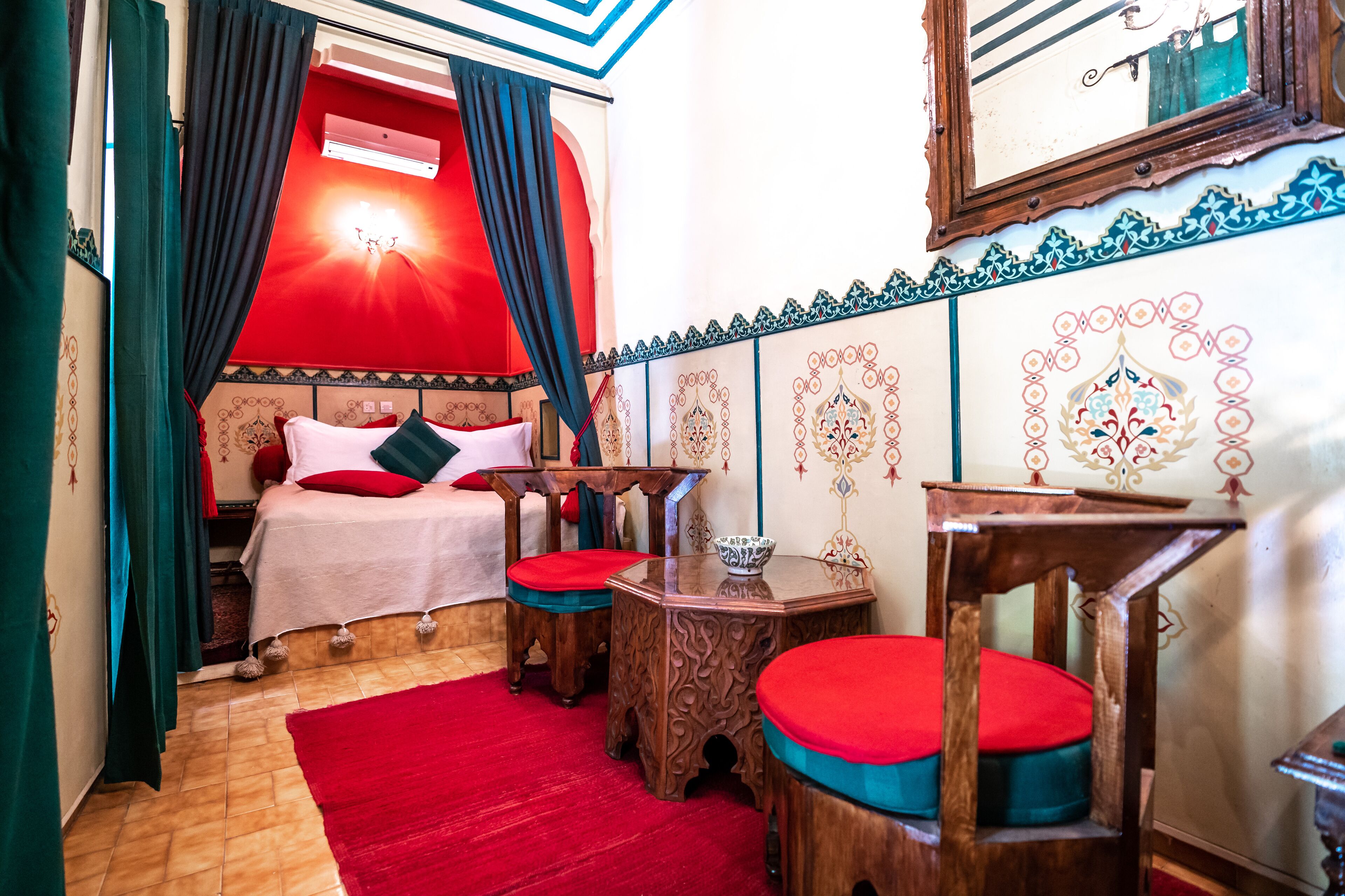 Una habitación con una cama, una mesa de madera y un tapete rojo.