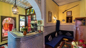A room with a blue and white patterned sofa, a tiled bar area, and a decorative ceiling. - Hotel Sherazade (Marrakech)