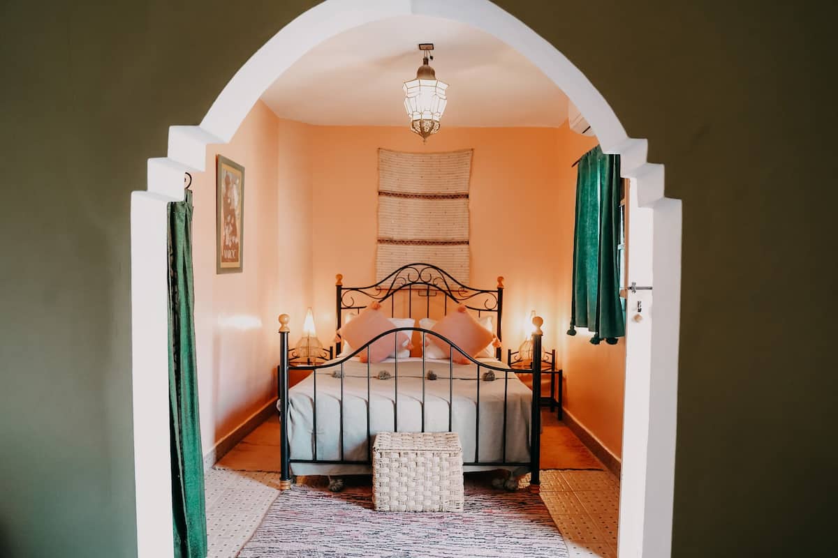 A bedroom with a bed, a chandelier, and a woven basket.