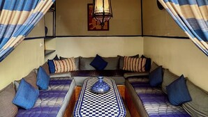A cozy room with a checkered table, cushioned seating, and striped curtains. - Hotel Sherazade (Marrakech)