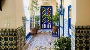 A corridor with patterned tiles, a blue door, and potted plants. - Hotel Sherazade (Marrakech)