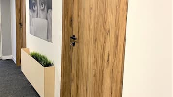 A hallway with wooden doors, a grey carpet, and a wall-mounted planter with green plants.