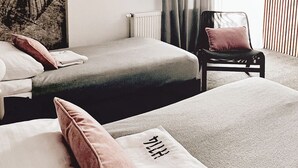 Habitación de hotel con dos camas, una silla, un radiador, un cuadro abstracto grande y una ventana con cortinas.