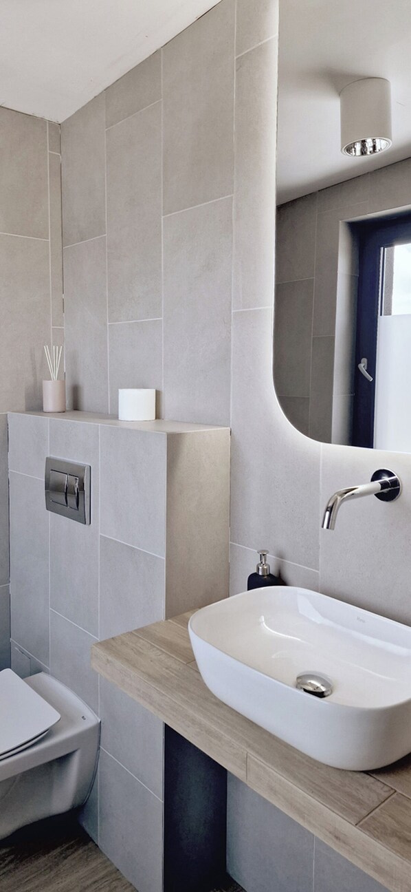 A modern bathroom with a large mirror, a white sink, and a toilet. - Wygodne Pokoje H114 (Gliwice)