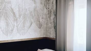 Une chambre d’hôtel moderne avec un grand mur à texture, un lit avec une tête de lit, une table de chevet et un luminaire suspendu.