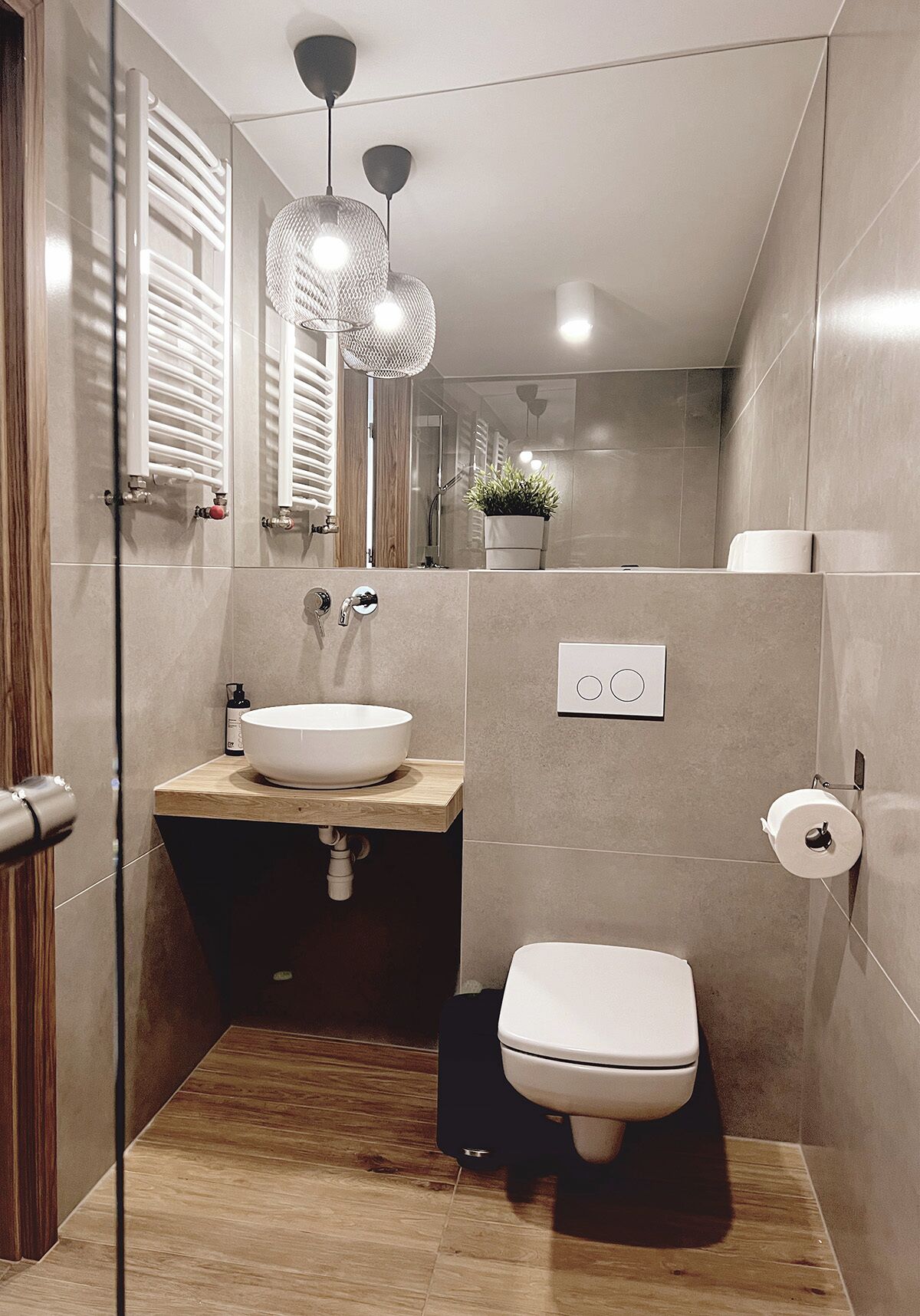 Ein modernes Badezimmer mit einem Holzwaschtisch, einem weißen Waschbecken, einer Toilette und einer Duschkabine.