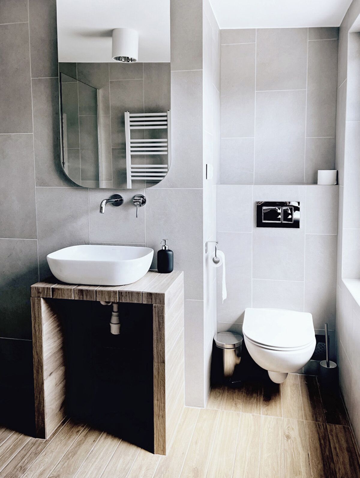 Une salle de bain moderne avec un grand lavabo, un miroir et des toilettes.