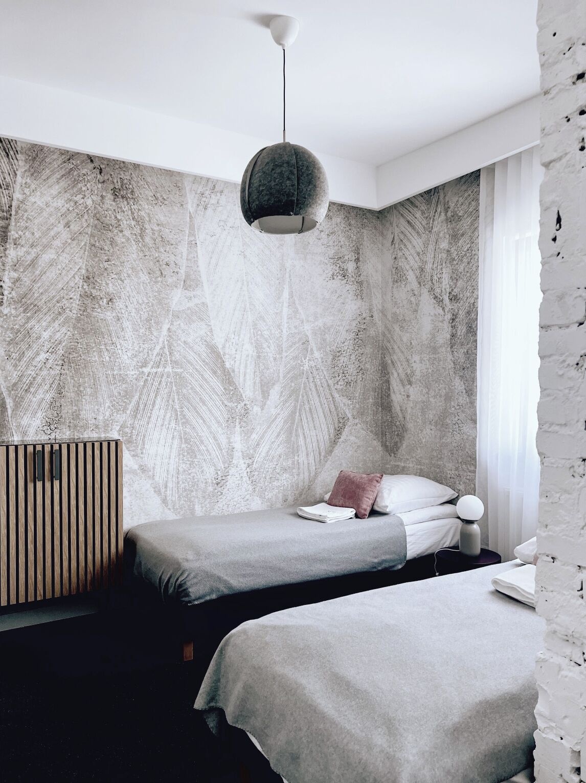 Un dormitorio moderno con un mural grande en la pared, una lámpara colgante y un aparador de madera.