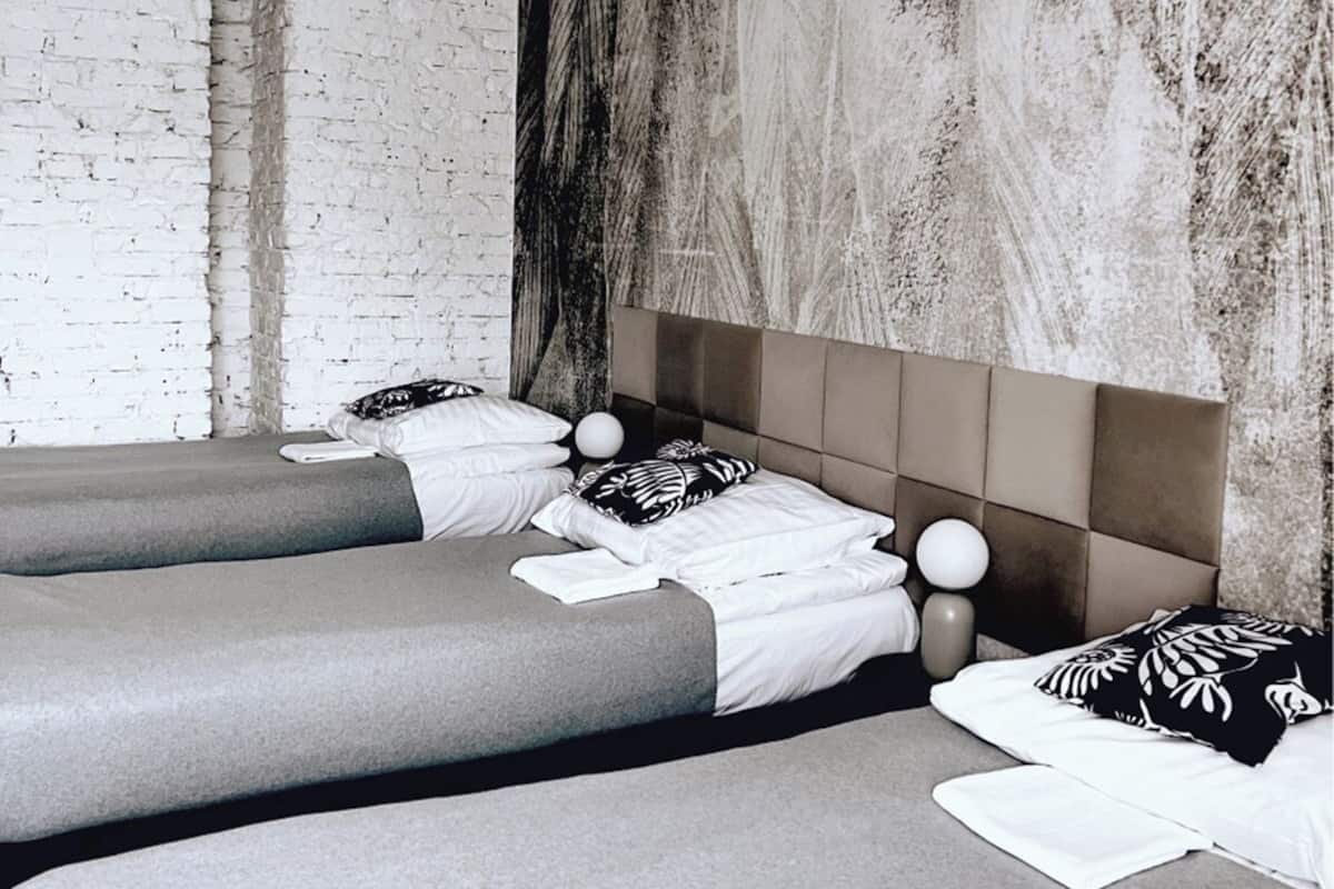 A modern hotel room with a large bed, a smaller bed, and a seating area.