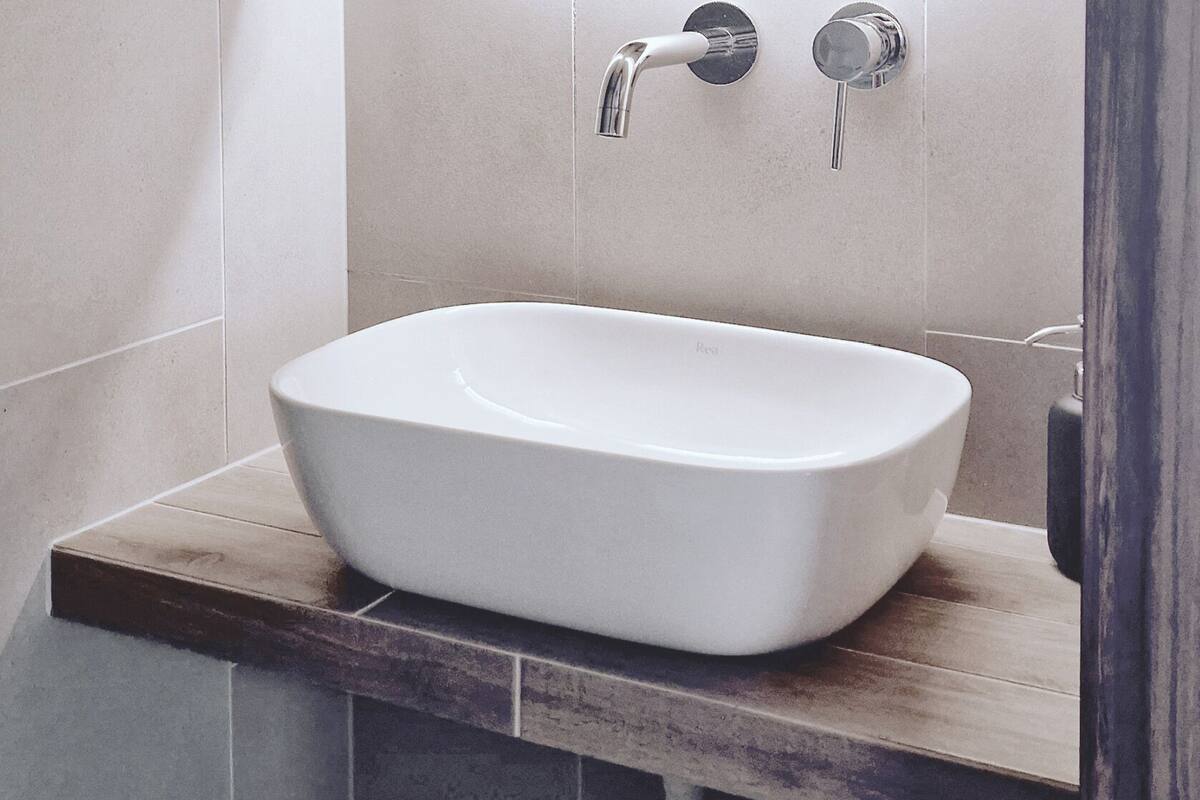 A modern bathroom with a large mirror, a vessel sink, and a wooden countertop.