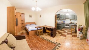 Habitació petita amb llit, escriptori i cadira, una cuineta i zona de menjador.