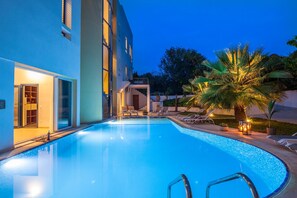 Una piscina al aire libre, sillones reclinables de piscina