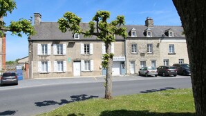 A street view with a row of stone buildings, a tree in the foreground, and parked cars.