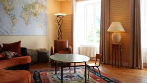 A cozy living room with a round table, a globe map on the wall, and a patterned rug.
