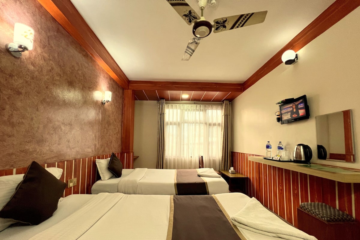 A hotel room with two beds, a ceiling fan, a TV, and a minibar.
