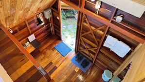 A compact, wooden interior with a kitchenette, a small bathroom, and a door leading outside. - JoyStay - Hostel (Hai Phong)