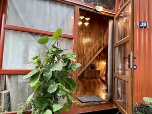Un interior de madera con una escalera, una puerta marcada J8 y una planta en maceta.