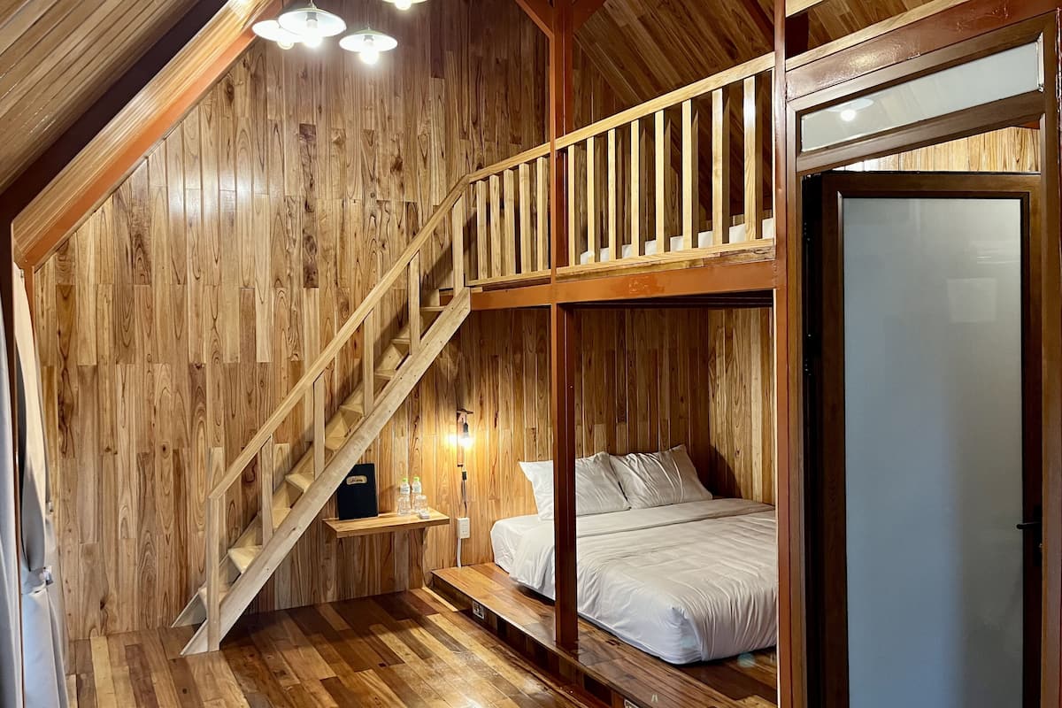 A wooden interior with a bunk bed, a staircase, and a glass door.
