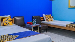 A hotel room with two single beds, a small table with water bottles, and a chair.