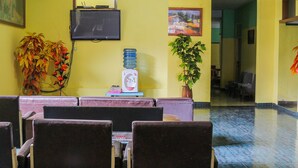 A reception area with a TV, a water dispenser, and a plant.