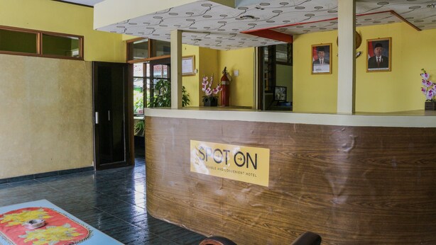 A hotel reception desk with a wooden finish and a sign that reads "SPOT ON".