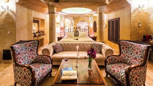 A luxurious room with a large bed, two armchairs, a coffee table, and a fireplace. - Zeydem Suites (Ürgüp)