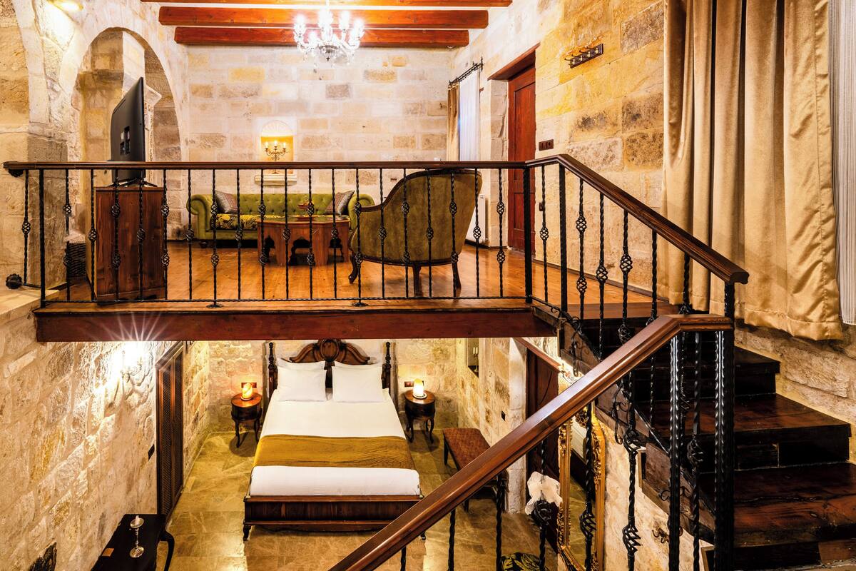 Habitación de hotel con balcón, cama, sofá y escalera.