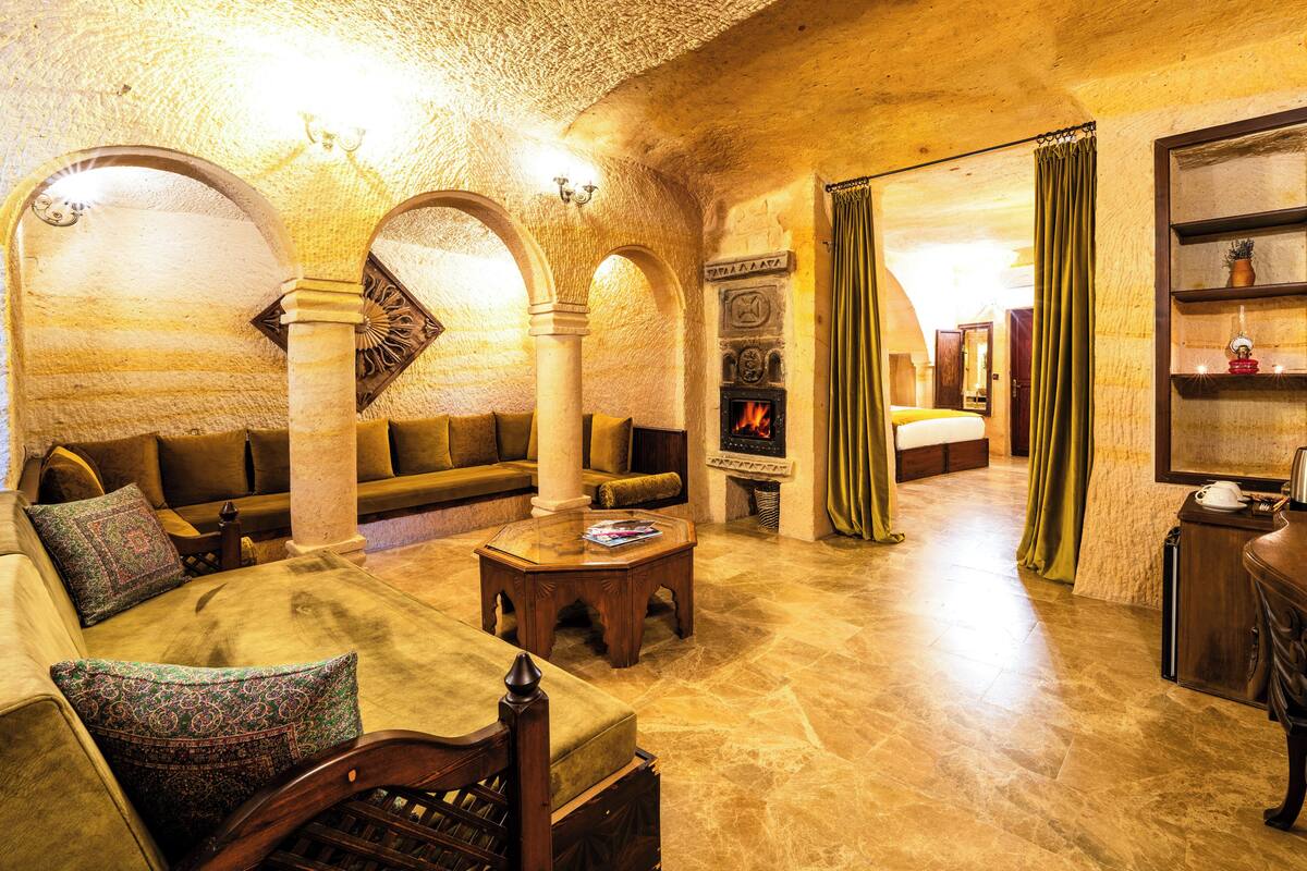 Una habitación con paredes de piedra, una chimenea, un sofá, una mesa de centro y una estantería.