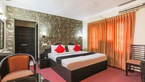 A hotel room with a bed, two bedside tables, a chair, a desk, and a mirror. - RamKripa Inn (Karwi)