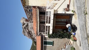 Un edificio con fachada de piedra, contraventanas de madera y techo de tejas.