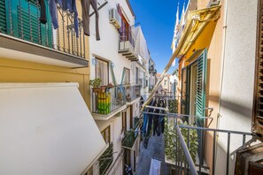 Uma viela estreita entre edifícios com varandas, algumas com roupas e plantas.