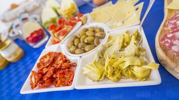 Une table garnie de divers aliments, notamment des olives, des artichauts et du fromage.