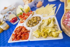 Uma mesa com diversos alimentos, incluindo azeitonas, alcachofras e queijo.