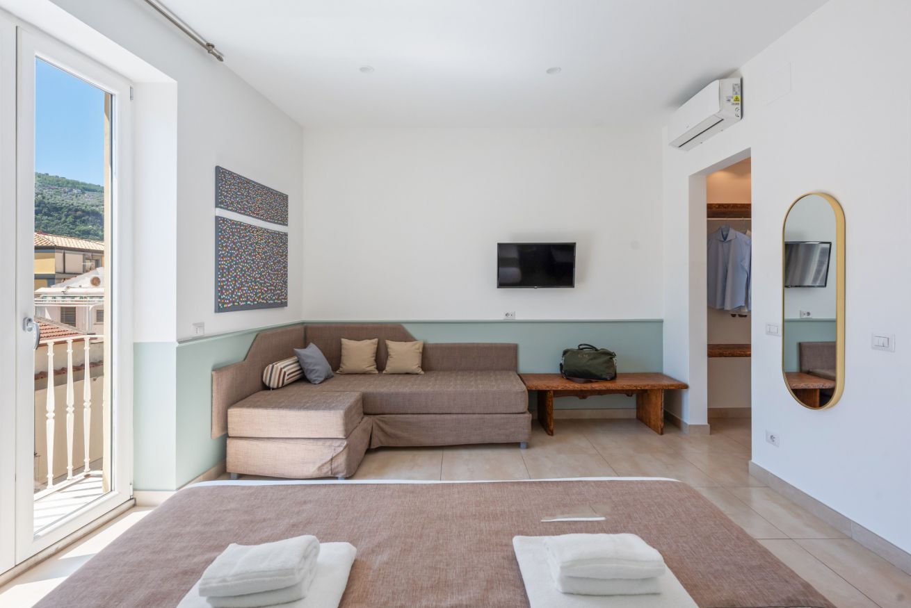 Un dormitorio moderno con una cama grande, un sofá, un televisor y un espejo.