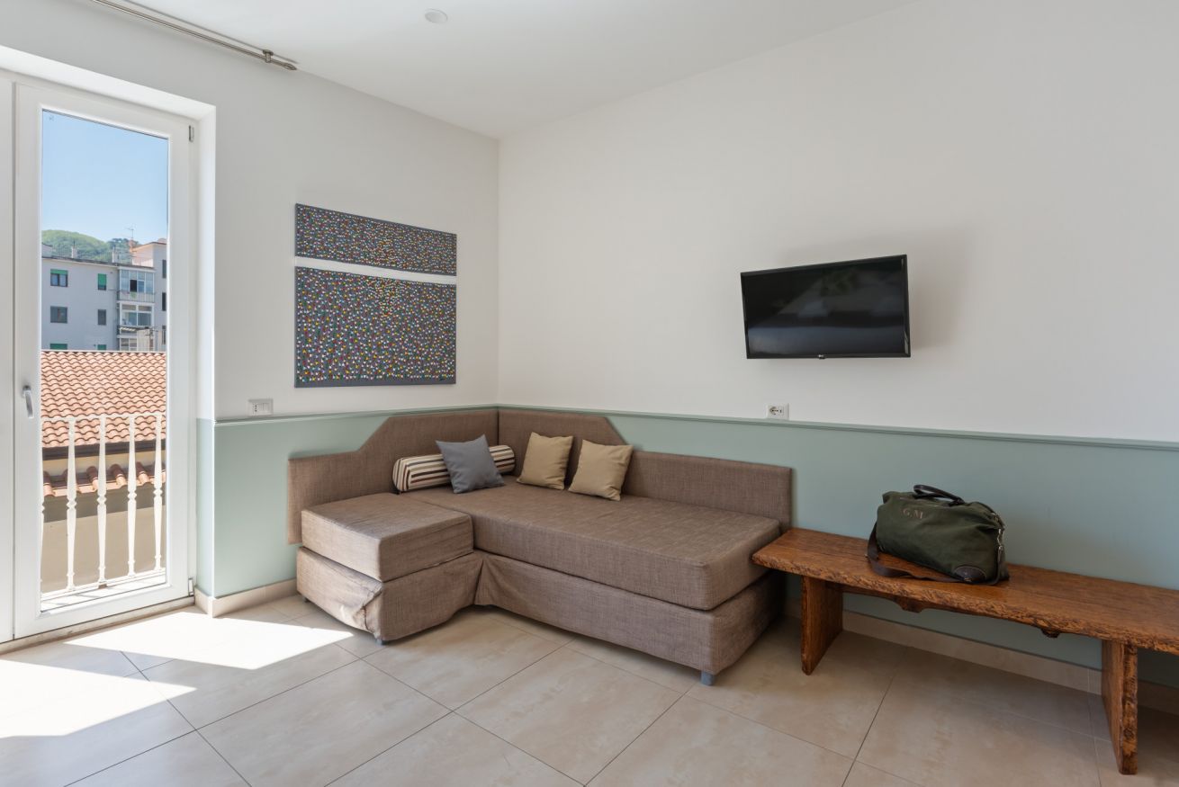 A living room with a sofa, a bench, a TV, and artwork on the wall.