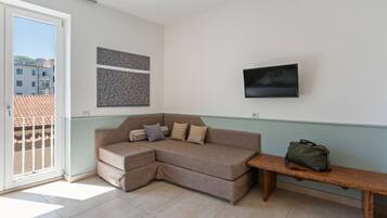 A living room with a sofa, a bench, a TV, and artwork on the wall.