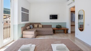 Ein modernes Schlafzimmer mit einem großen Bett, einer Couch, einem Fernseher und einem Spiegel.