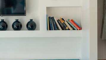 Un mur orné d’un téléviseur à écran plat, de trois vases noirs et d’une bibliothèque remplie de livres.