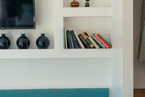 Una pared con un televisor de pantalla plana, tres jarrones negros y una estantería llena de libros.