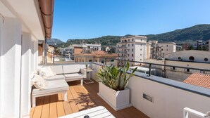 Un balcon avec un canapé blanc, une petite table et une plante en pot.