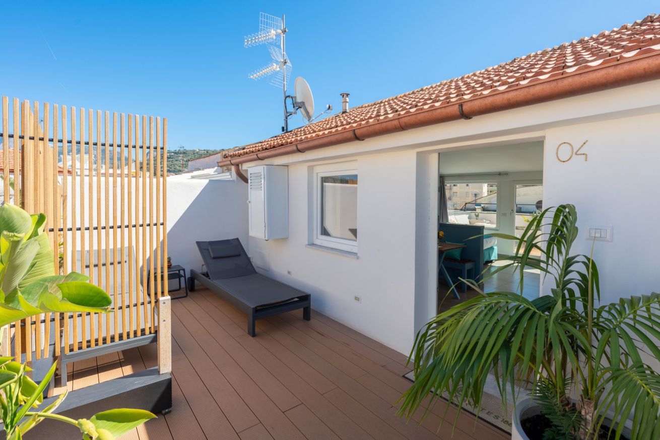 A modern outdoor deck with a lounge chair, a wooden fence, and a satellite dish.