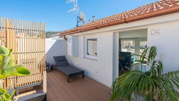 A modern outdoor deck with a lounge chair, a wooden fence, and a satellite dish.