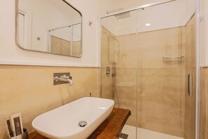 A bathroom with a white sink, a mirror, and a glass-enclosed shower.