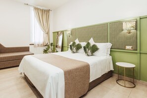 A hotel room with a large bed, a small sofa, a bedside table, and a window with curtains. - Modern & Elegant Suite in the heart of Sorrento (Sorrento)