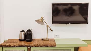 Una kitchenette con cafetera, hervidor y lámpara sobre una encimera de madera.